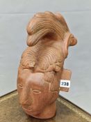 A TERRACOTTA HEAD OF AN INCAN WITH AN ELABORATE HAIR STYLE SWEPT UP INTO A CREST ABOVE HIS FOREHEAD.