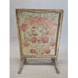 A GILT WOOD FIRESCREEN WITH THE NEEDLE WORK PANEL WORKED WITH RED CARNATIONS. 92 x 64cms.