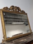 A VICTORIAN RECTANGULAR OVERMANTLE MIRROR, THE GILT FRAME CRESTED BY A SERPENTINE ARRANGEMENT OF