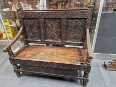 AN 18th C. OAK SETTLE, THE THREE CARVED PANEL BACK ABOVE A COFFER SEAT WITH A FRONT CARVED WITH A