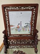 A CHINESE HARDWOOD SET FAMILLE ROSE PLAQUE PAINTED WITH TWO LADIES AND TWO CHILDREN ON A GARDEN