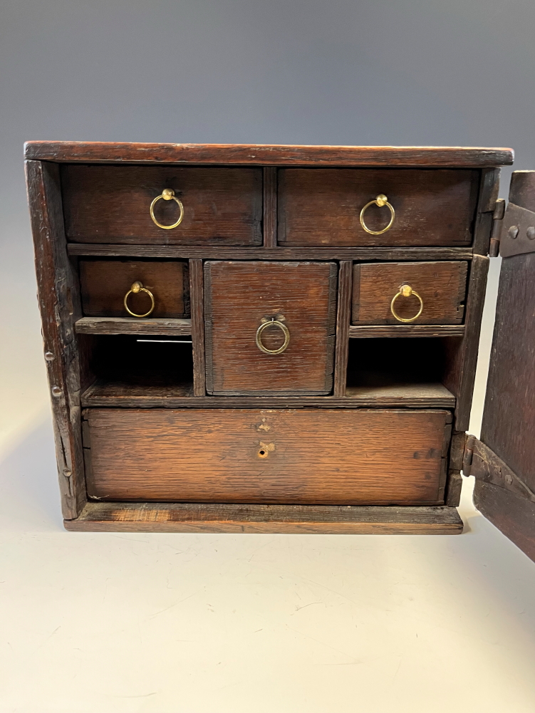 AN 18th C. OAK TABLE TOP CABINET, THE X-SHAPED PANELLED DOOR OPENING ONTO SIX DRAWERS AND TWO PIGEON - Image 5 of 14