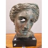 A BRONZED PLASTER HEAD OF A CLASSICAL LADY ON A BLACK PLINTH. H 44cms.