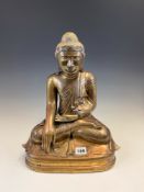 A POLISHED BRONZE BUDDHA, POSSIBLY BURMESE, WITH GLASS EYES BELOW A JEWELLED DIADEM, HE SITS IN