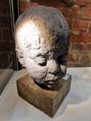 A SCULPTED HEAD OF A CHILD MOUNTED ON A SQUARE WOODEN PLINTH.   H 31cms.