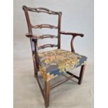 A GEORGE III MAHOGANY LADDER BACKED ELBOW CHAIR WITH A NEEDLE WORK SEAT ABOVE THE CANTED SQUARE