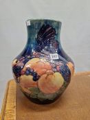 A WALTER MOORCROFT VASE SLIP TRAILED WITH BIRDS AMONGST FRUIT ON A SHADED BLUE GROUND. H 34cms.