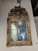 A 18th CENTURY RECTANGULAR MIRROR WITHIN A SILVERED FRAME CARVED WITH SHELL SHAPES BELOW AN ARCHED