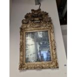 A 18th CENTURY RECTANGULAR MIRROR WITHIN A SILVERED FRAME CARVED WITH SHELL SHAPES BELOW AN ARCHED