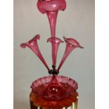A LATE VICT0RIAN CRANBERRY GLASS EPERGNE, THE CENTRAL TRUMPET VASE FLANKED BY THREE SMALLER, ALL