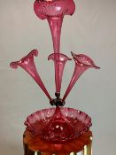 A LATE VICT0RIAN CRANBERRY GLASS EPERGNE, THE CENTRAL TRUMPET VASE FLANKED BY THREE SMALLER, ALL