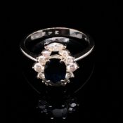 A SAPPHIRE AND DIAMOND CLUSTER RING. THE OVAL SAPPHIRE IN A FOUR CLAW SETTINGS, SURROUNDED BY TWO