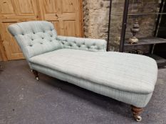 A VICTORIAN CHAISE LONGUE BUTTON UPHOLSTERED IN PALE BLUE, THE TURNED FRONT LEGS ON WHITE CERAMIC