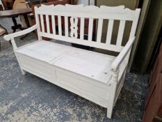 A WHITE PAINTED PINE BENCH, THE SLATTED BACK OVER A COMPARTMENTAL SEAT BETWEEN THE ARMS. W 153cms.