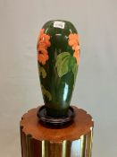 A MOORCROFT TABLE LAMP, THE GREEN SLENDER OVOID SHAPE SLIP TRAILED WITH IRISES. H 32cms. WITH A WOOD