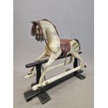 A DAPPLED GREY ROCKING HORSE WITH BRIDLE AND SADDLE, THE SUPPORTING TRESTLE BLACK