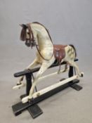 A DAPPLED GREY ROCKING HORSE WITH BRIDLE AND SADDLE, THE SUPPORTING TRESTLE BLACK