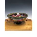 A WILLIAM MOORCROFT POMEGRANATE FOOTED BOWL, THE FRUIT SLIP TRAILED ONTO AN OLIVE GREEN GROUND. Dia.