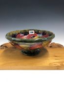 A WILLIAM MOORCROFT POMEGRANATE FOOTED BOWL, THE FRUIT SLIP TRAILED ONTO AN OLIVE GREEN GROUND. Dia.