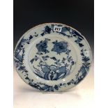 AN ENGLISH DELFT BLUE AND WHITE DISH CENTRALLY PAINTED WITH TWO STEMS OF FLOWERS GROWING AMONGST