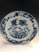 AN ENGLISH DELFT BLUE AND WHITE DISH CENTRALLY PAINTED WITH TWO STEMS OF FLOWERS GROWING AMONGST