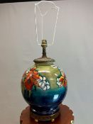 A MOORCROFT TABLE LAMP SLIP TRAILED WITH IRISES AND OTHER FLOWERS ON AS SHADED TURQUOISE GREEN