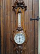 A LATE VICTORIAN OAK CASED ANEROID BAROMETER WITH THERMOMETER OVER.