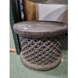 A BAMILEKE BLACK STOOL, THE DISHED CIRCULAR TOP ABOVE DIAMOND DIAPER PIERCED AND BOSS CENTRED SIDES.