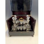 A 19th C. FRENCH EBONISED DECANTER BOX, THE LID LIFTING UP TO REVEAL FOUR ENGRAVED GLASS DECANTERS