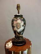 A MOORCROFT TABLE LAMP, THE BALUSTER BODY SLIP TRAILED WITH SPIKEY FLOWERS ON A DEEP GREEN GROUND. H