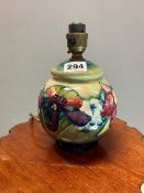 A MOORCROFT COMPRESSED SPHERICAL TABLE LAMP SLIP TRAILED WITH IRISES AND OTHER FLOWERS AGAINST A