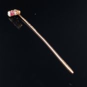A DIAMOND AND RUBY STICK PIN. THE THREE GEMS SET IN CLAW SETTINGS UPON A TRADITIONAL PIN.