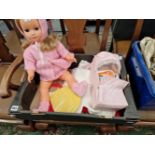 A PLASTIC DOLL WITH HAND KNITTED CLOTHES AND A SMALL CARRY COT WITH FURTHER CLOTHES