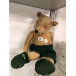 A 20th C. TEDDY BEAR WEARING GREEN WOOLEN SHORTS AND SOCKS