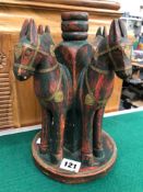 AN EASTERN CARVED WOOD HORSE CANDLE STAND.