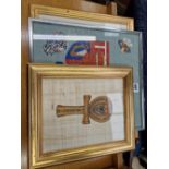 A NEEDLE WORK OF A PAIR OF ARMORIAL SHIELDS, A PENCIL SIGNED PRINT AND AN EGYPTIAN CRUCIFORM PAINTED