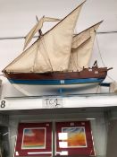 A WOODEN MODEL SHIP IN FULL SAIL WITH A BLUE AND WHITE HULL