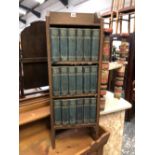 A SET OF 18 DICKENS NOVELS IN SMALL OAK ARTS AND CRAFTS BOOKCASE.