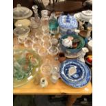 A BLUE AND WHITE POTTERY SOUP TUREEN, PLATES, DECANTERS, CHAMPAGNE GLASSES, GLASS TRUMPET CENTRE