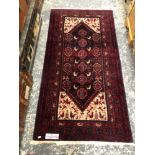 AN EASTERN HAND WOVEN RED GROUND SMALL CARPET 186 X 97CMS.