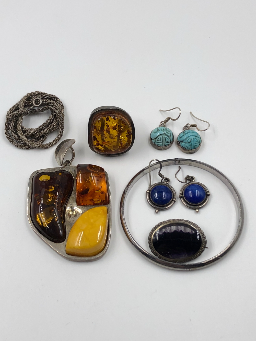 A COLLECTION OF SILVER JEWELLERY TO INCLUDE A LARGE MULTI AMBER PENDANT, AN AMBER RING, CARVED