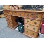 AN OAK PEDESTAL DESK, THE KNEEHOLE DRAWER FLANKED BY BANKS OF FOUR