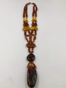 A VINTAGE MULTI COLOUR AMBER NECKLACE WITH LARGE NATURAL AMBER STRUNG PENDANT. LENGTH 54cms,