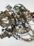 A COLLECTION OF COSTUME JEWELLERY TO INCLUDE EARRINGS, BEADS, CHAINS, CERAMIC FLORAL BROOCH ETC.