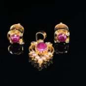 A RUBY AND DIAMOND PENDANT AND EARRING SUITE. THE PENDANT CENTERING A CABOCHON OVAL CUT RUBY IN A