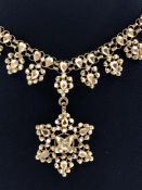 A TRADITIONAL INDIAN NECKLACE OF PIERCED AND FACETED DESIGN SUSPENDED ON A WOVEN LARIAT STYLE