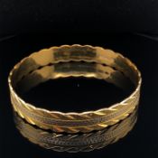 A TWO COLOUR ORNATE CONTINUOUS BANGLE. THE INSIDE MARKED 22K, WITH TWO SETS OF EASTERN CHARACTER
