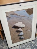 A FRAMED PHOTOGRAPH OF THREE HEART SHAPED STONES ON A BEACH