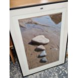 A FRAMED PHOTOGRAPH OF THREE HEART SHAPED STONES ON A BEACH