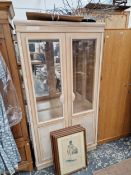 A LIMED WOOD DISPLAY CUPBOARD, THE UPPER PANELS OF THE DOORS GLAZED ABOUT SHELL HANDLES, REEDED